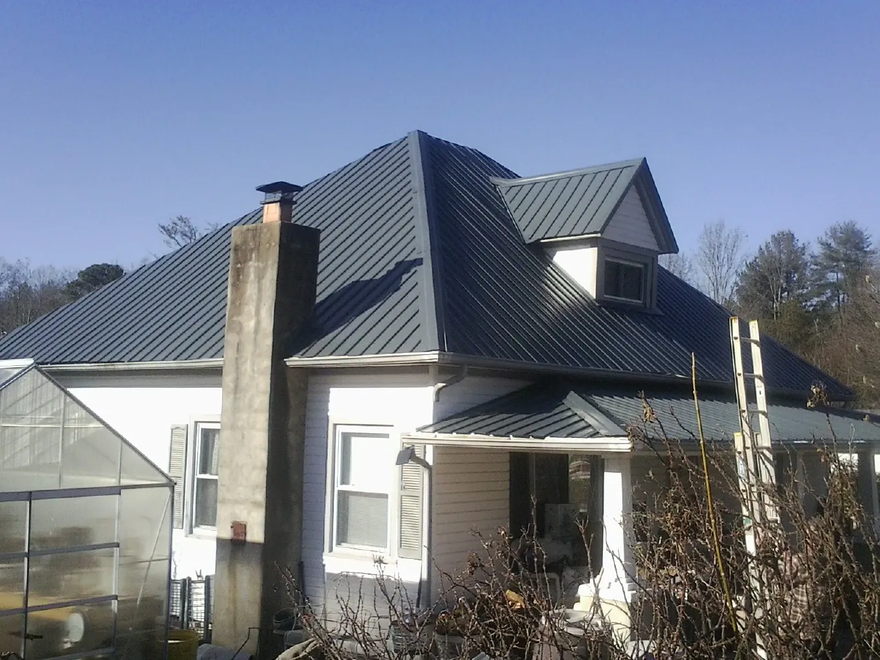 Dark blue standing seam metal roof on a white farmhouse with dormer — Slate & Tile Roof Repair by Roofing Brothers in Cawood