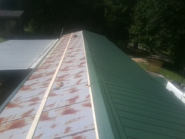 Old rusted panels beside newly installed green metal roofing — Wind Damage Roof Repair by Roofing Brothers in Cawood