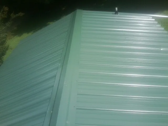 New green metal panels meeting at the ridge of a roof — Flat Roof Repair work by our crew in Cawood