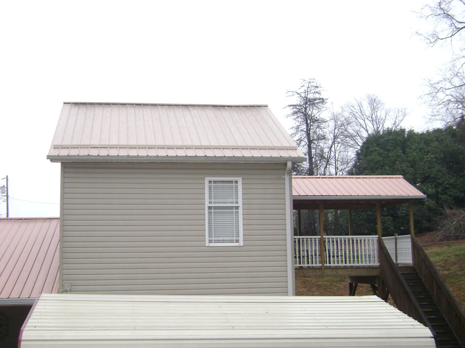 Tan metal roofs on a two story addition and attached porch, from a Roof Replacement job in Cawood