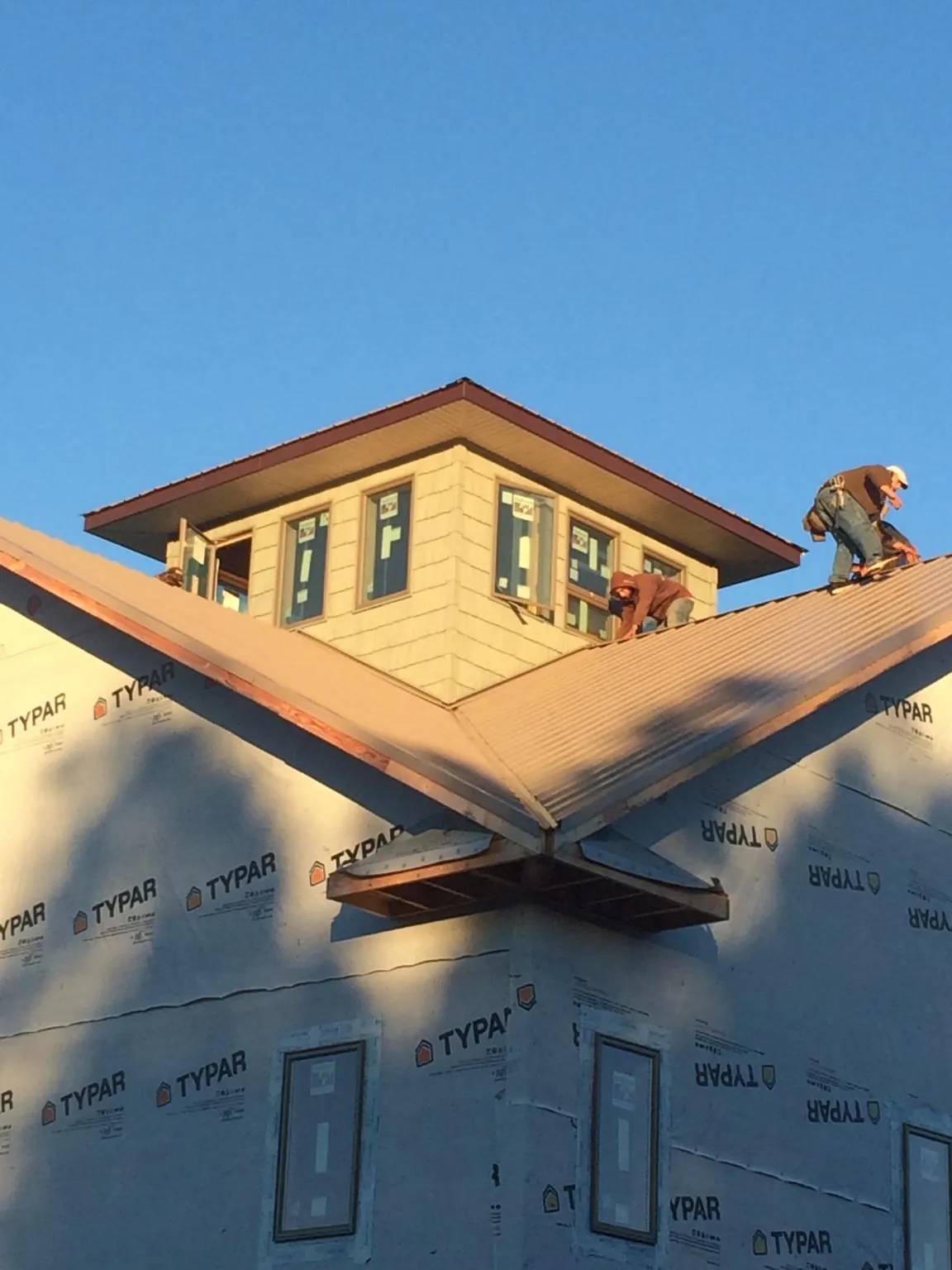 Roofers working around a rooftop cupola on a new metal roof at sunset — Roof Waterproofing in Cawood by Roofing Brothers